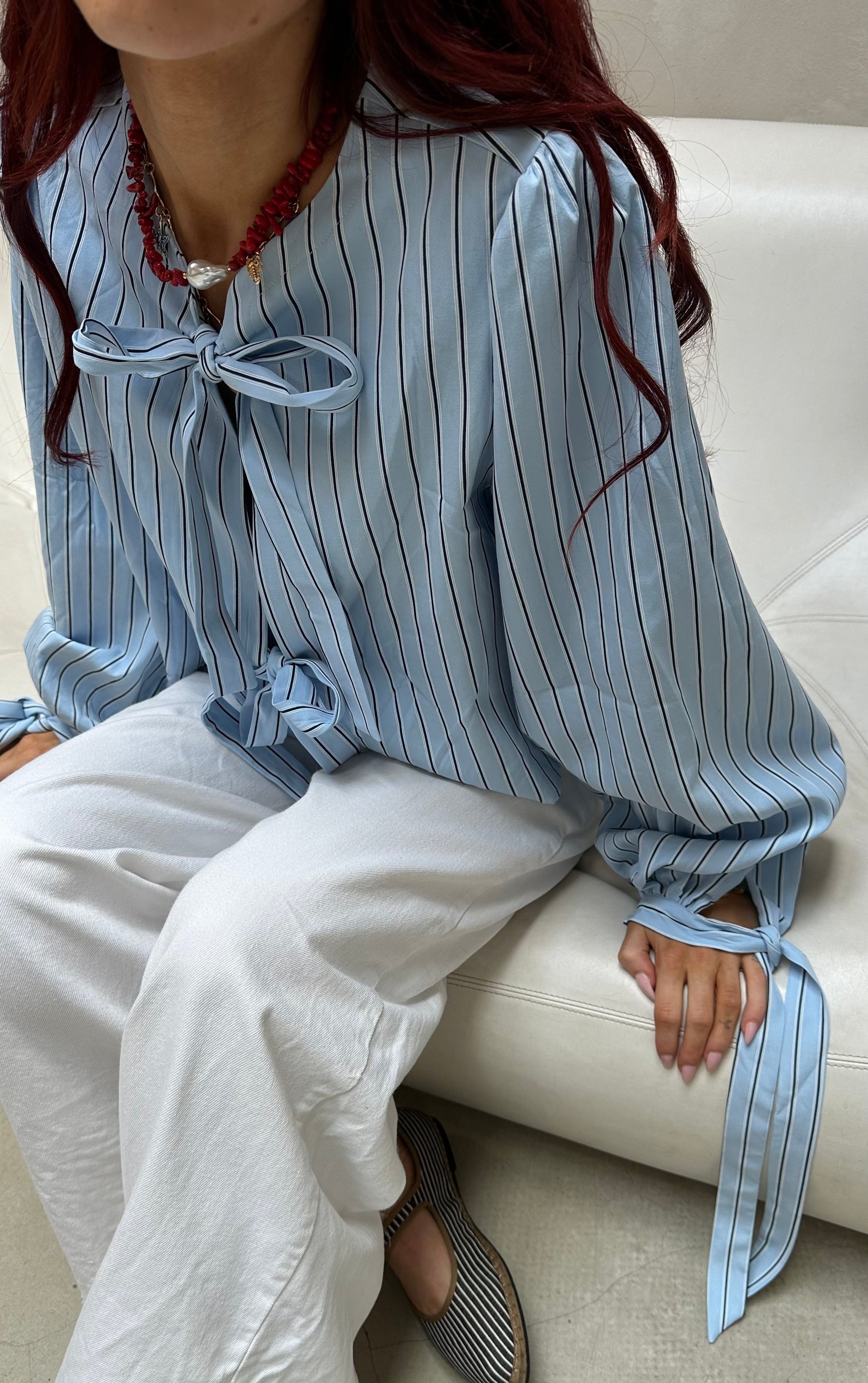 Person wearing a blue striped shirt with a bow tie sitting on a white couch.