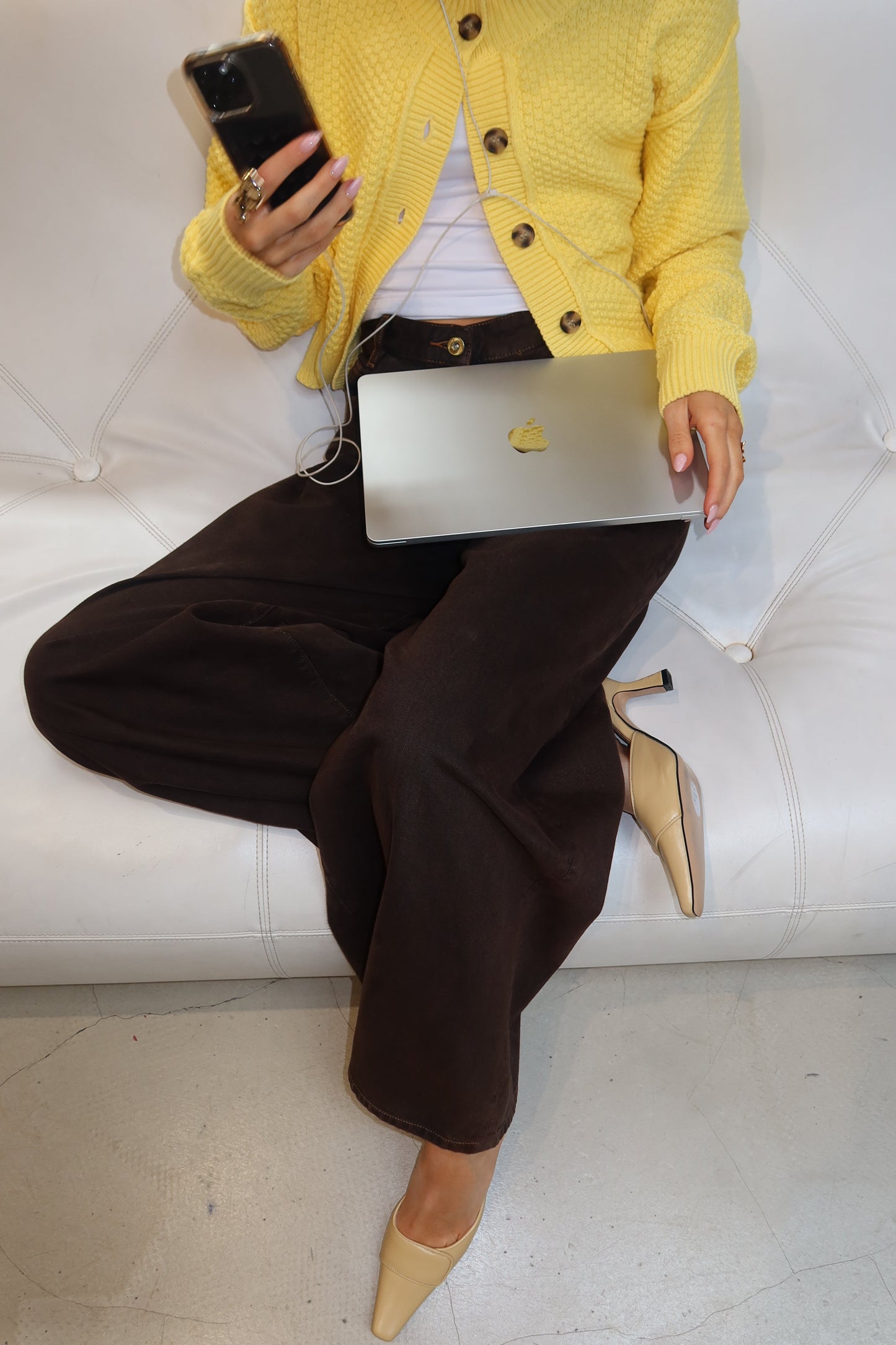 Person in yellow jacket using a laptop on a white couch