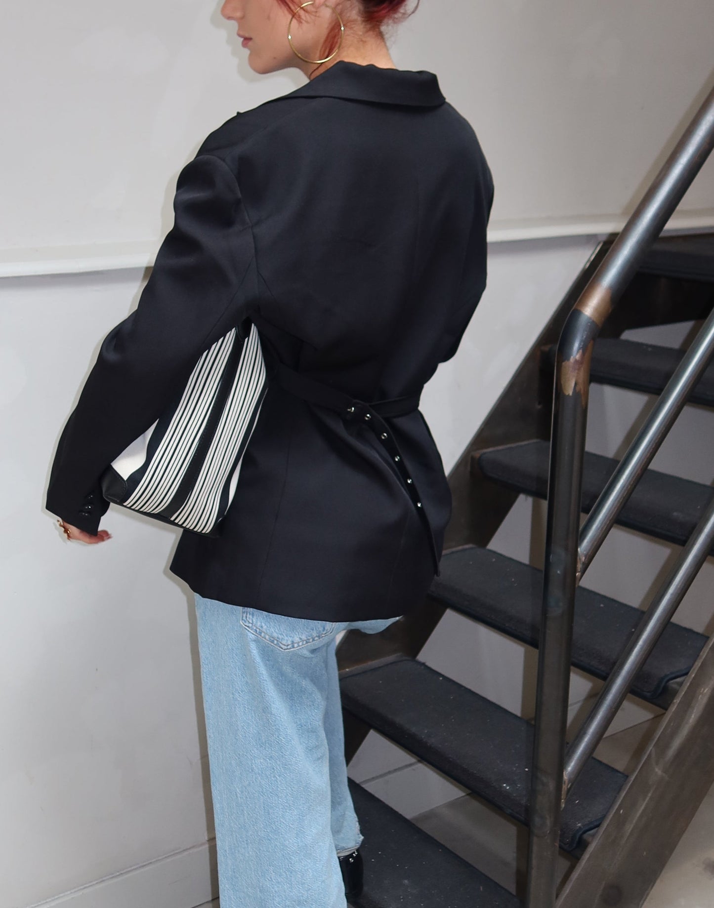 Person with red hair standing on a staircase in an indoor setting