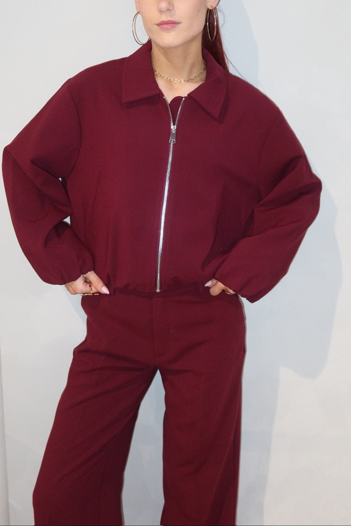 Person wearing a burgundy tracksuit against a plain background