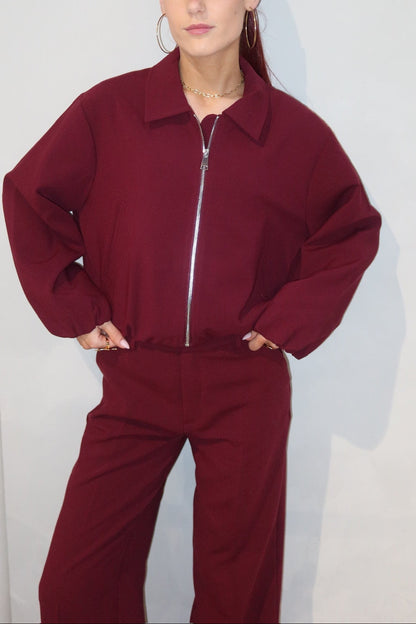 Person wearing a burgundy tracksuit against a plain background