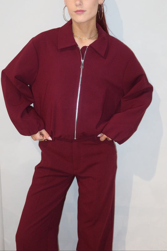 Person wearing a burgundy tracksuit against a plain background