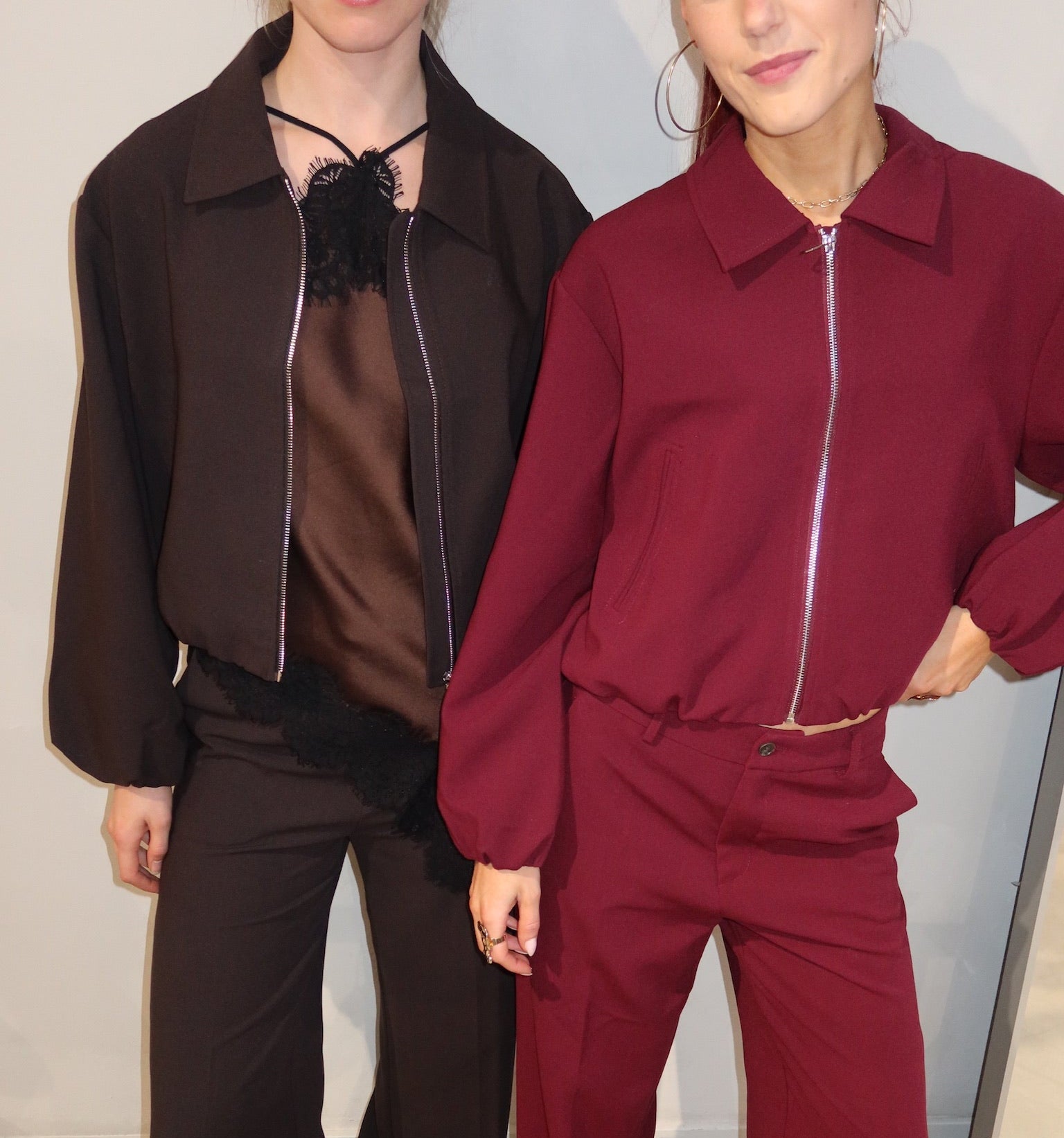 Two people wearing brown and red outfits standing side by side.