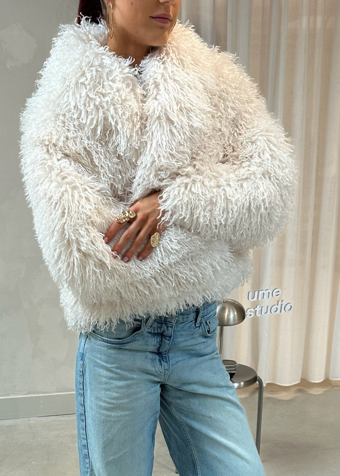 Person wearing a fluffy white sweater and blue jeans standing in front of a mirror.