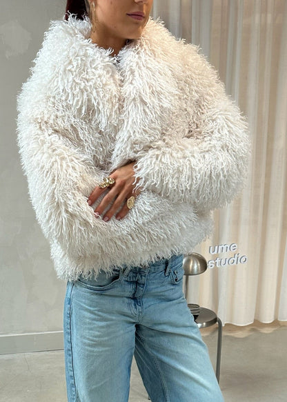 Person wearing a fluffy white sweater and blue jeans standing in front of a mirror.